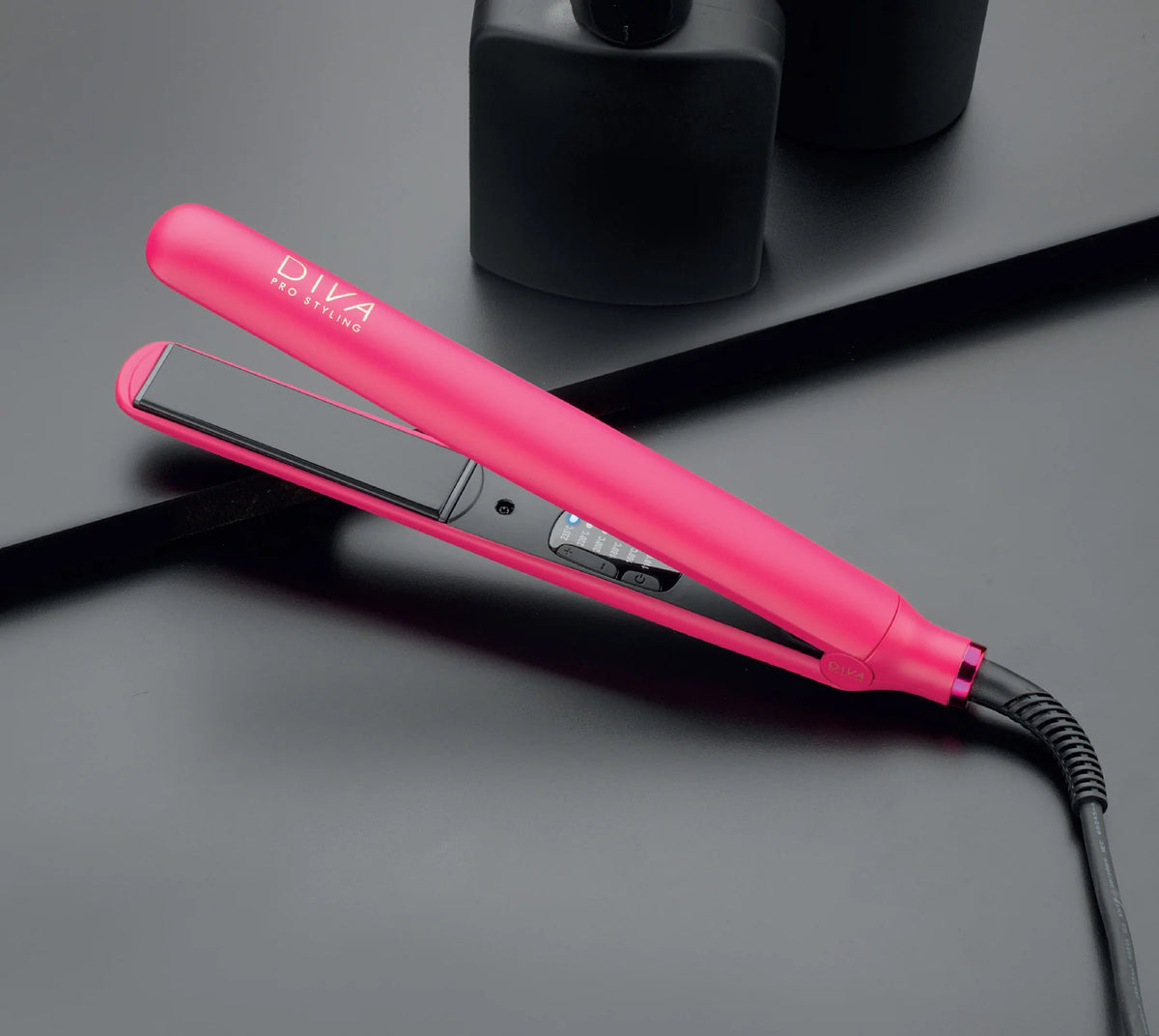A digital hair straightener in a vibrant magenta color with a ceramic floating plate, displayed on a black surface, likely a part of a gift set.