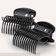 A pair of black plastic hair roller grips designed to hold rollers for creating curls.