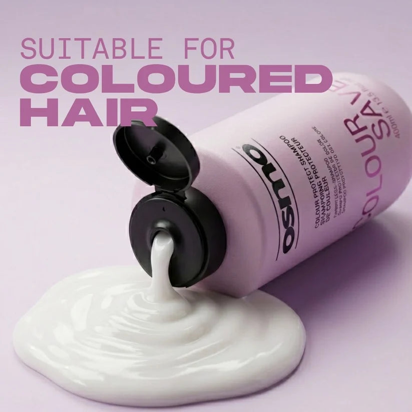 A bottle of Oliso Colour Save shampoo is shown tilted on a light lavender background, with white shampoo cream pouring out onto a pool below. Large pink text at the top reads 'SUITABLE FOR COLOURED HAIR'.