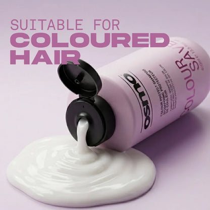 A bottle of Oliso Colour Save shampoo is shown tilted on a light lavender background, with white shampoo cream pouring out onto a pool below. Large pink text at the top reads 'SUITABLE FOR COLOURED HAIR'.
