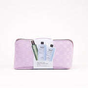 A lavender and white checkered cosmetic pouch with a zipper closure, featuring a white paper insert in front displaying two skincare bottles from REF. The pouch is photographed on a clean white background.