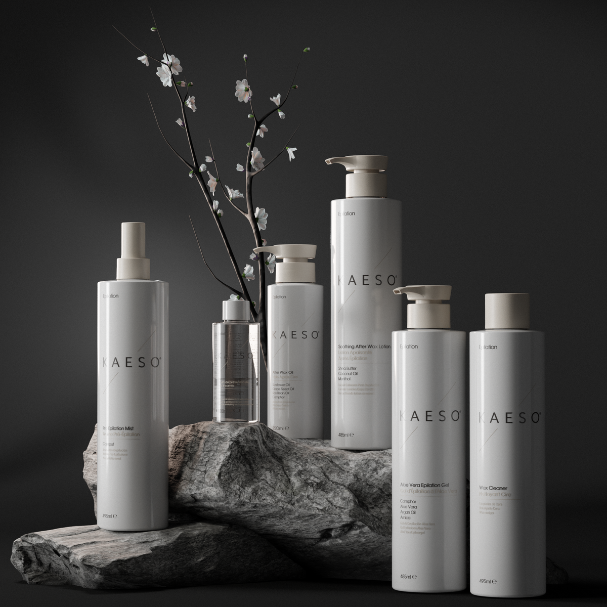 Six Kaeso epliation hair removal products in minimalist white and silver packaging are arranged on a dark stone pedestal with a small flowering branch behind them against a dark studio background.