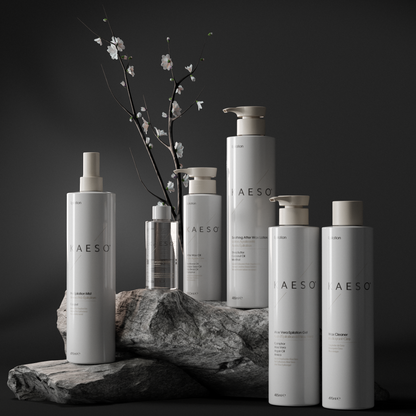 Six Kaeso epliation hair removal products in minimalist white and silver packaging are arranged on a dark stone pedestal with a small flowering branch behind them against a dark studio background.