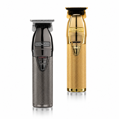 Two handheld hair clippers shown on a clean white background: one in dark metallic gray and one in polished gold. Both have the visible brand name 'Babyliss PRO' on the front.