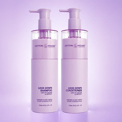 Two white plastic bottles of Leyton House Lock Down Shampoo and Lock Down Conditioner with pump dispensers, set against a soft lavender studio background.