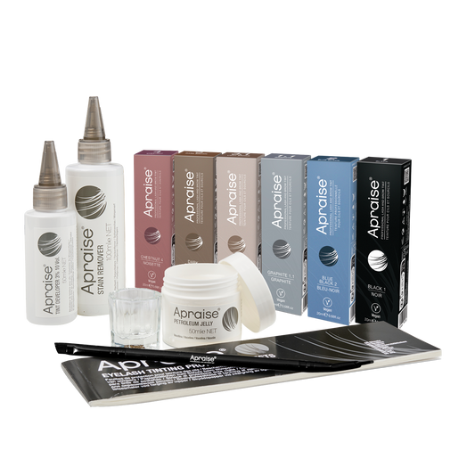 A collection of Aprise hair extension products, including two white bottles with silver applicator tips, several colored boxes in pink, brown, beige, gray, blue, and black, a white jar with its lid off, a small clear mixing cup, and black-and-white instruction sheets on a plain white background.
