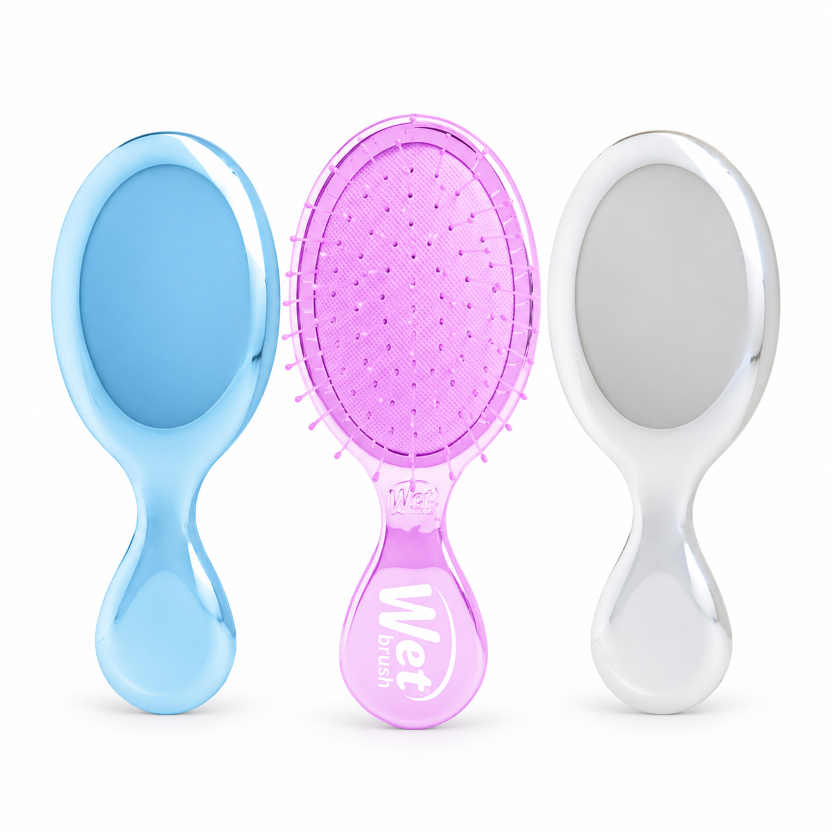 Three oval-shaped hairbrushes with glossy handles are shown side by side on a white background. The left brush has a light blue handle, the center brush has a purple handle with a purple bristle heads, and the right brush has a silver handle.