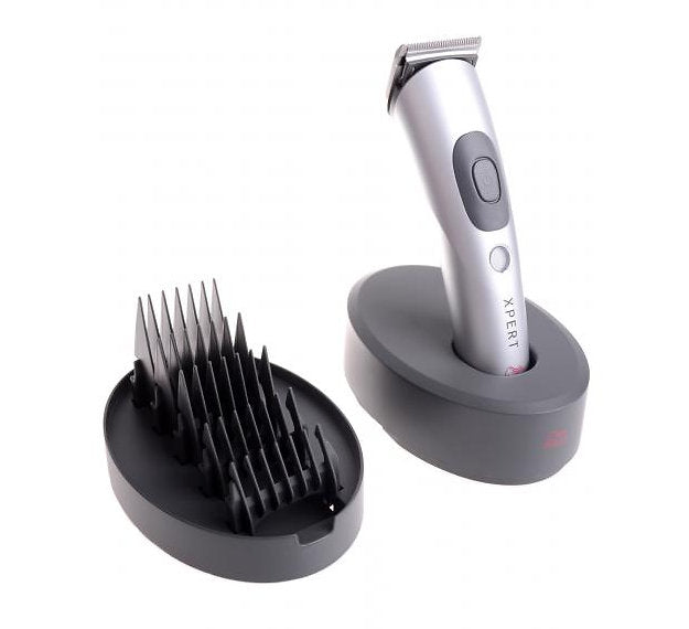 A silver and gray cordless hair trimmer standing on a matching charging base, shown next to a black comb guard attachment on a clean white background. The trimmer has the brand name 'XPERT' printed vertically on its side.
