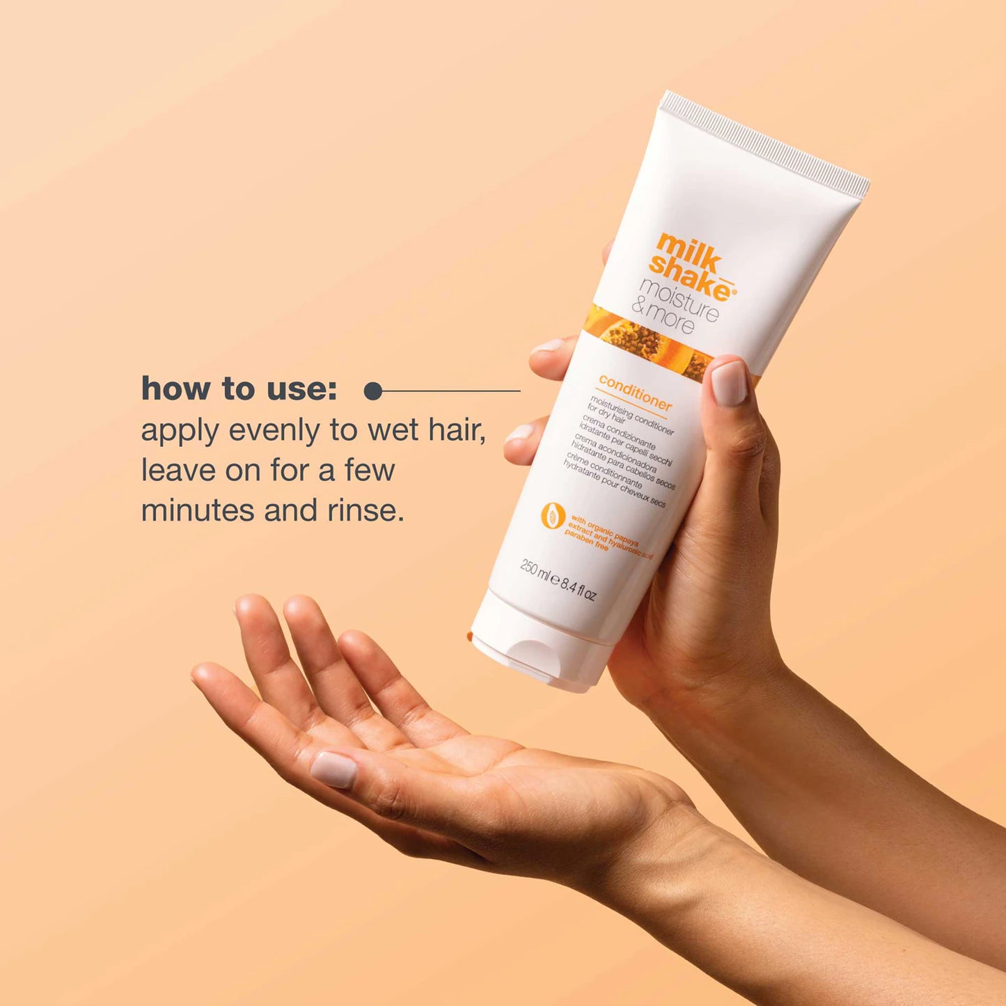 Hand holding a tube of milk shake conditioner with application instructions on a beige background