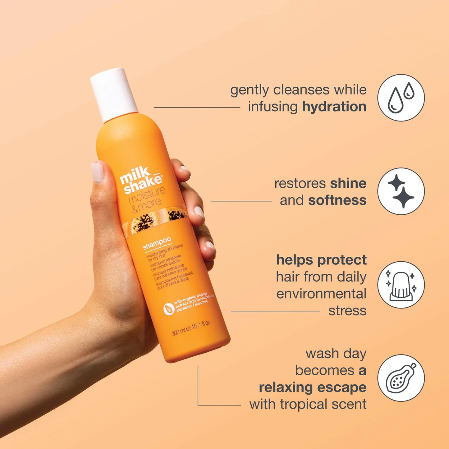 Orange shampoo bottle held by a hand with product features on a beige background