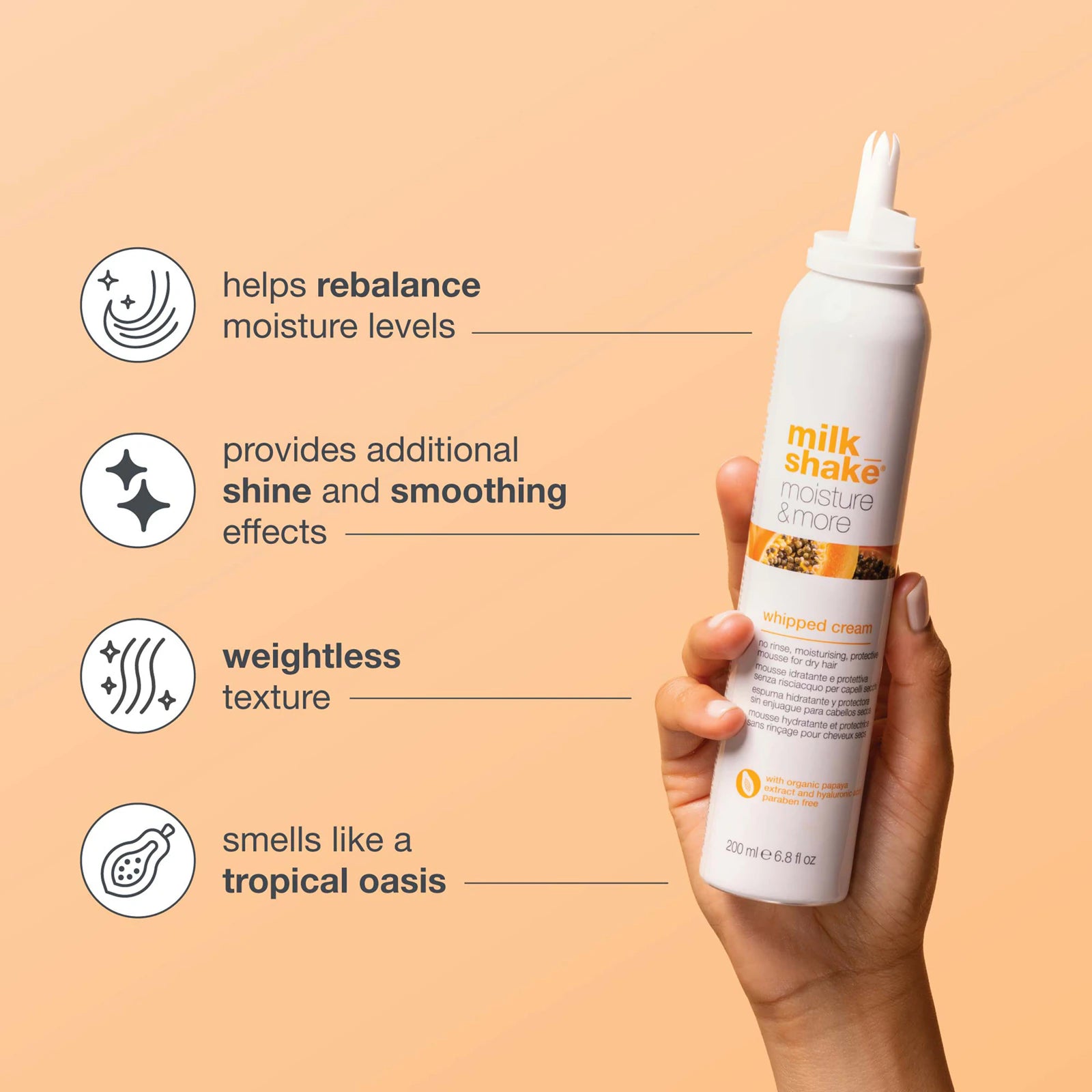 Hand holding a bottle of 'milk shake' hair product with text on a peach background