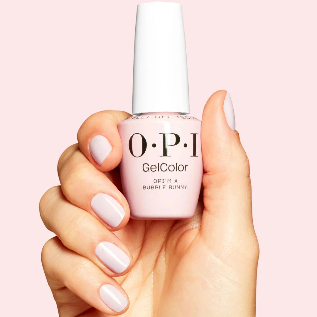 Hand holding a bottle of OPI nail polish with matching nail color on a pink background