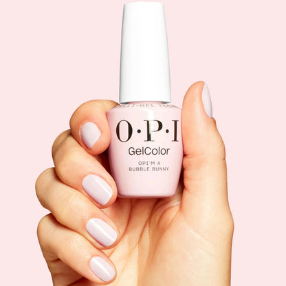 Hand holding a bottle of OPI nail polish with matching nail color on a pink background