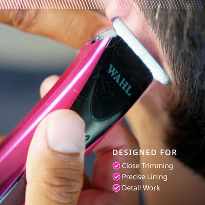 A close-up of a Wahl electric hair trimmer being used on a person's head, with a pink and black body and a silver blade. Text on the image reads 'DESIGNED FOR Close Trimming, Precise Lining, Detail Work'.